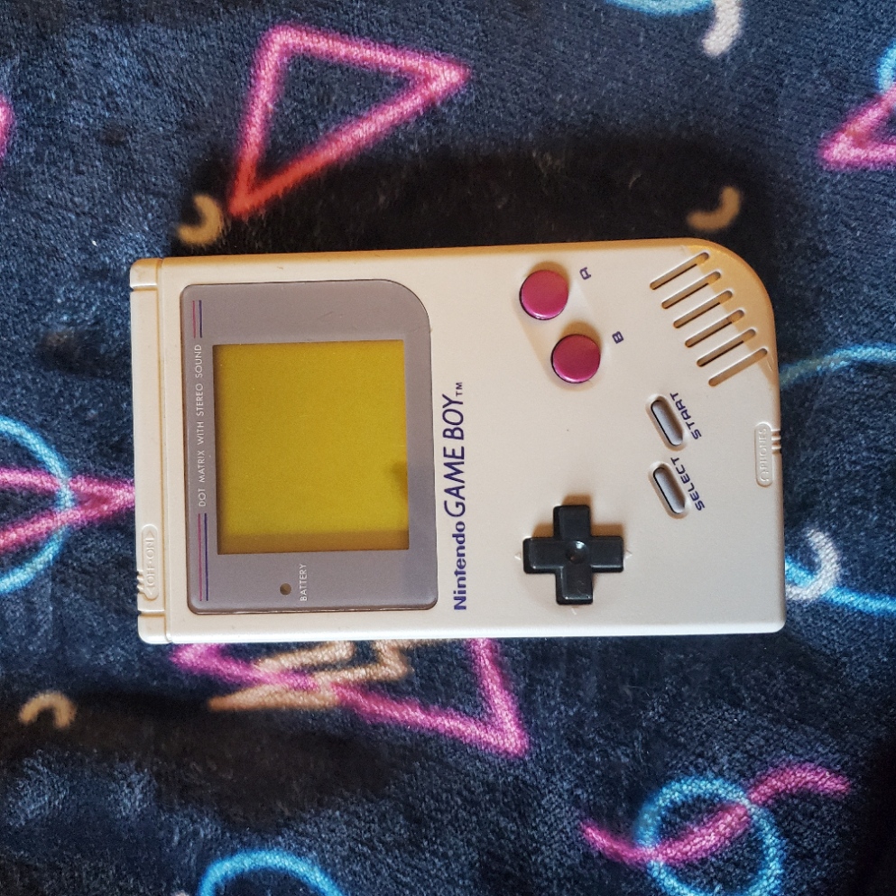 Grey Gameboy DMG on an arcade floor background