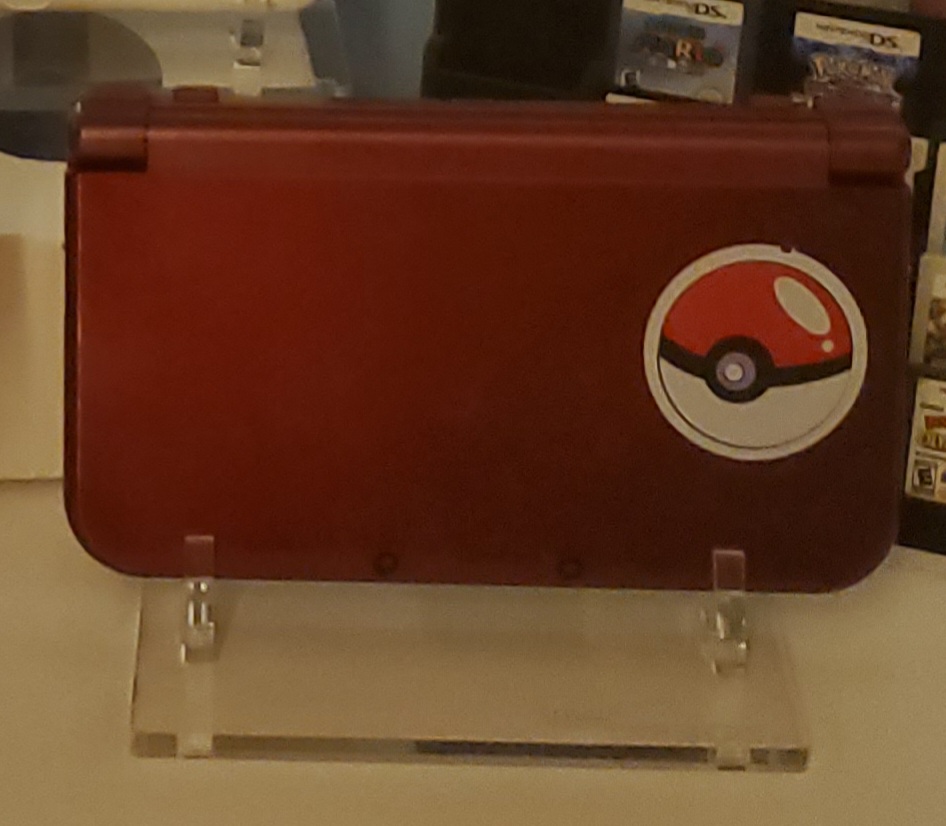 red new nintendo 3ds xl with a pokeball sticker on it