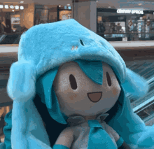 hatsune miku plush with a blue hat on. the hat has little arms and it is flapping them