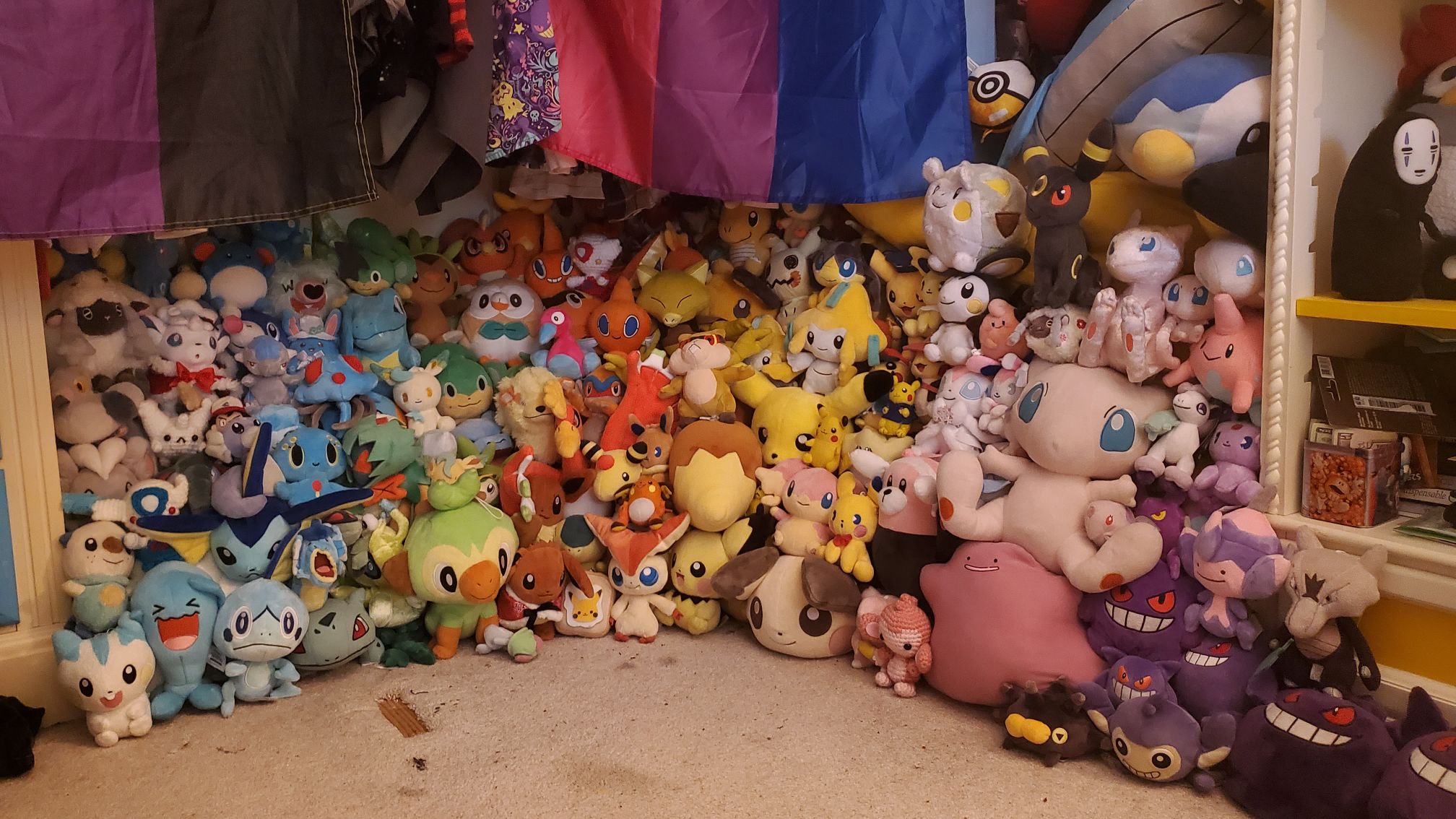 huge pile of pokemon plush, with a bisexual flag in the background
